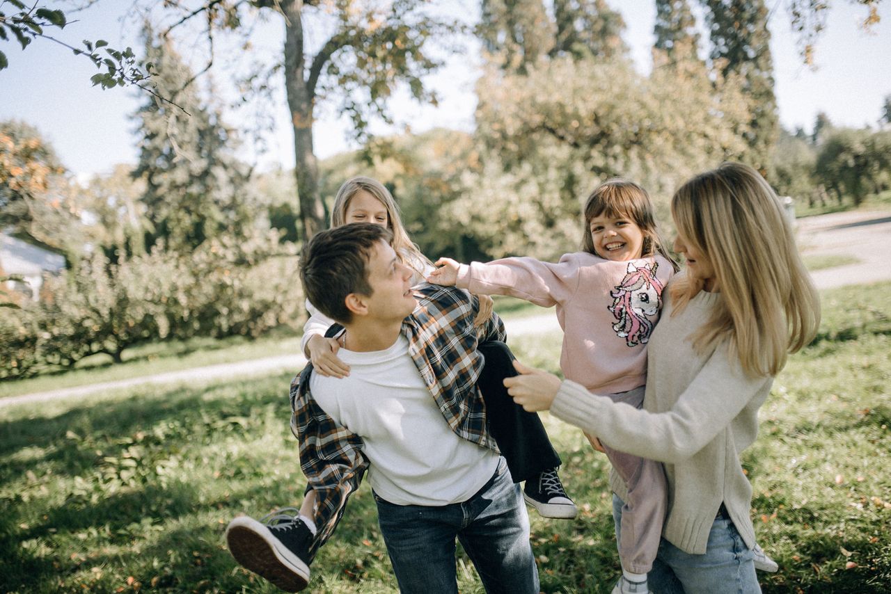 Oferta A joyful family spending quality time together in a green park on a sunny day.