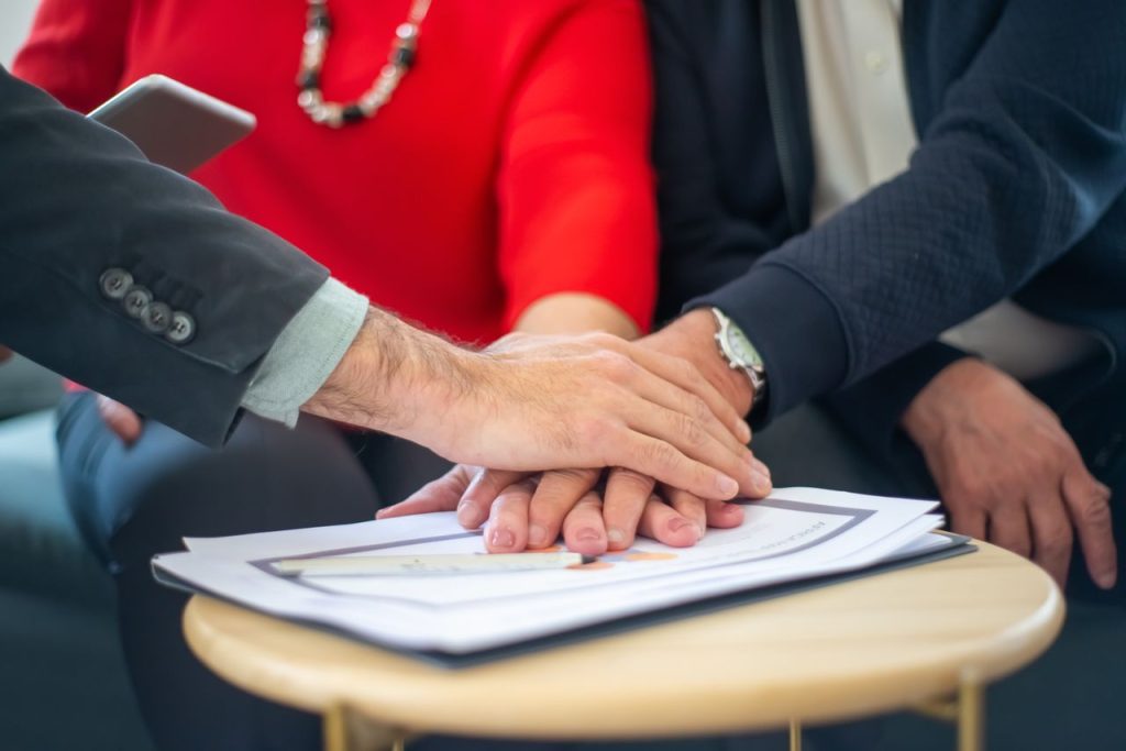 outdoor-image-02 Business professionals collaborating, with hands united over important documents, symbolizing teamwork and unity.